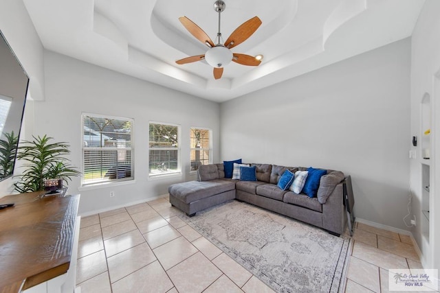 tiled living room with a raised ceiling and ceiling fan