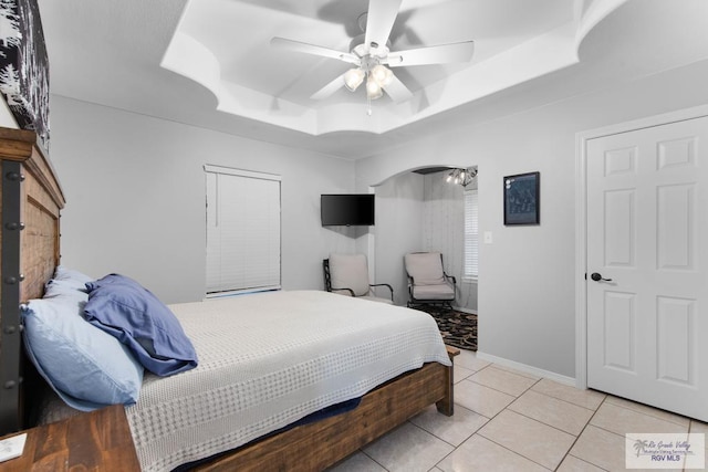 tiled bedroom with a raised ceiling and ceiling fan