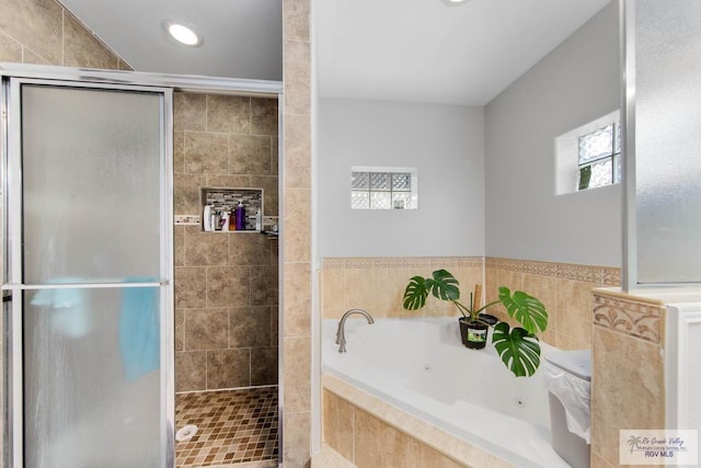 bathroom featuring plus walk in shower and tile walls