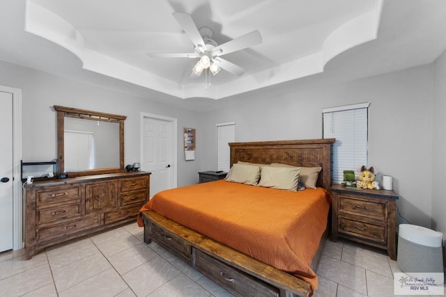 tiled bedroom featuring a raised ceiling and ceiling fan