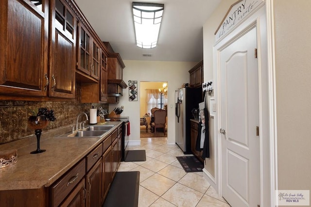 31660 Fm 1575, Los Fresnos, TX 78566 - kitchen featuring range with electric stovetop, a sink, light tile patterned floors, tasteful backsplash, and dark brown cabinets