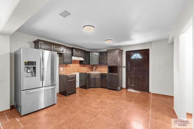 2307 Carlos Ave, Brownsville, TX 78526 - kitchen featuring light countertops, dark brown cabinetry, a sink, under cabinet range hood, and stainless steel fridge with ice dispenser