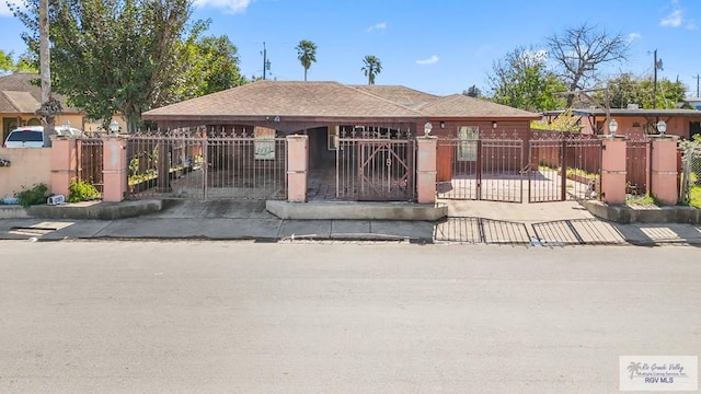 view of front of home with a fenced front yard, a gate, and a shingled roof