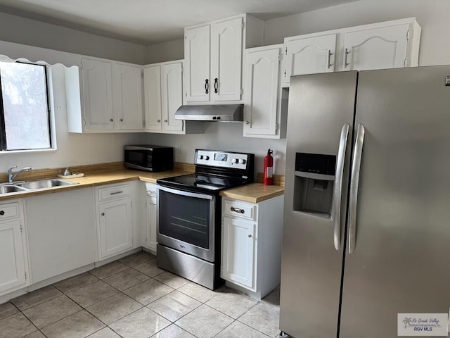 kitchen with sink, light tile patterned flooring, white cabinets, and appliances with stainless steel finishes