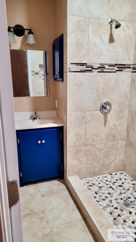 bathroom featuring tiled shower and vanity