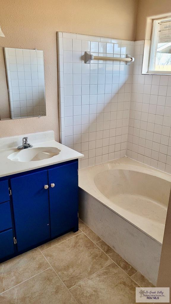 bathroom with tile patterned flooring, vanity, and a washtub