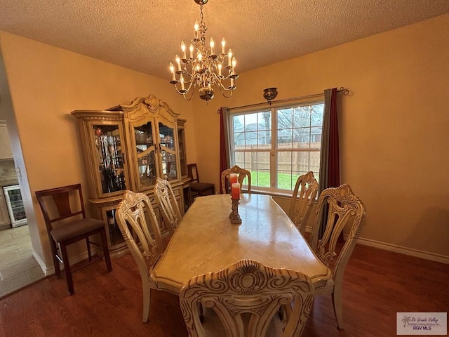 dining area featuring hardwood / wood-style flooring, an inviting chandelier, wine cooler, and a textured ceiling