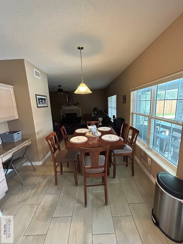 dining space featuring vaulted ceiling and a textured ceiling