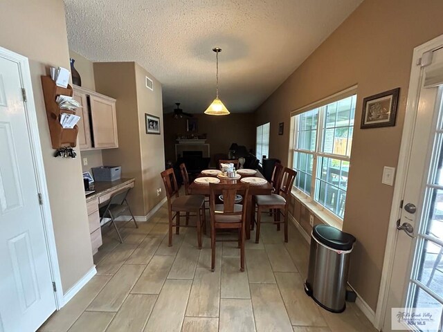 dining room with ceiling fan, vaulted ceiling, and a textured ceiling