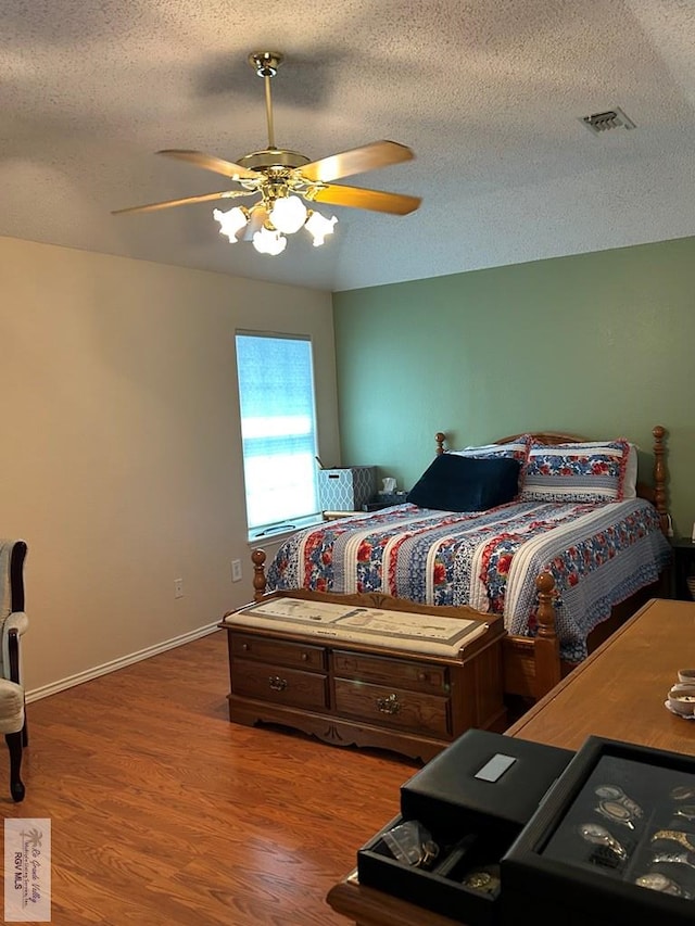 bedroom with hardwood / wood-style flooring, ceiling fan, and a textured ceiling