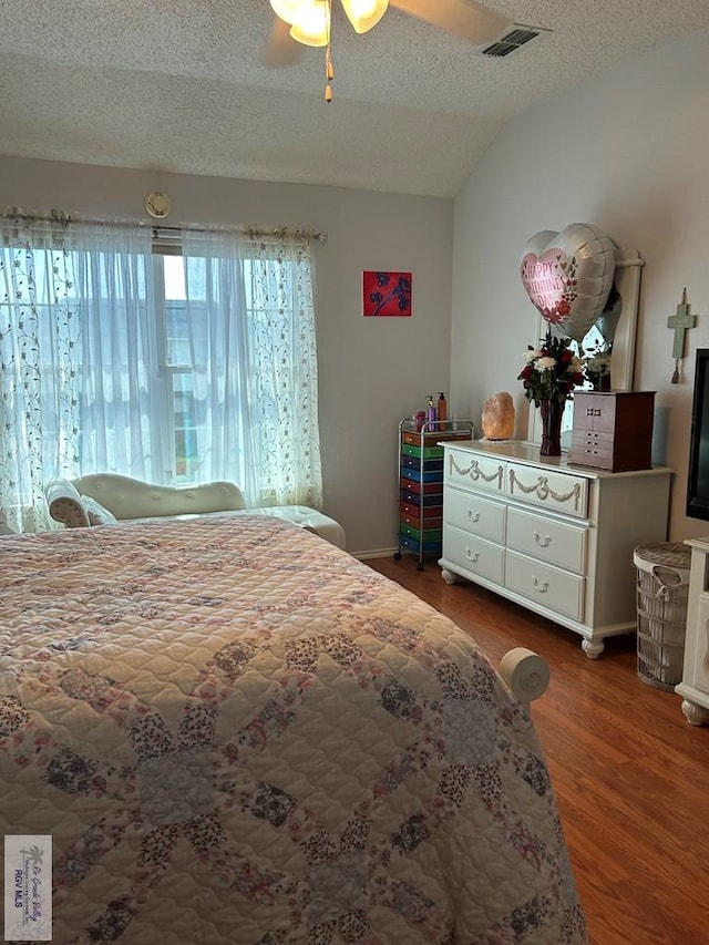 bedroom with ceiling fan, vaulted ceiling, dark hardwood / wood-style floors, and a textured ceiling