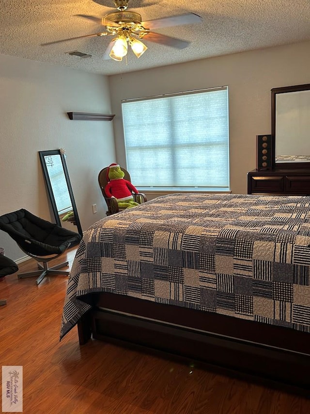 bedroom with hardwood / wood-style floors, a textured ceiling, and ceiling fan