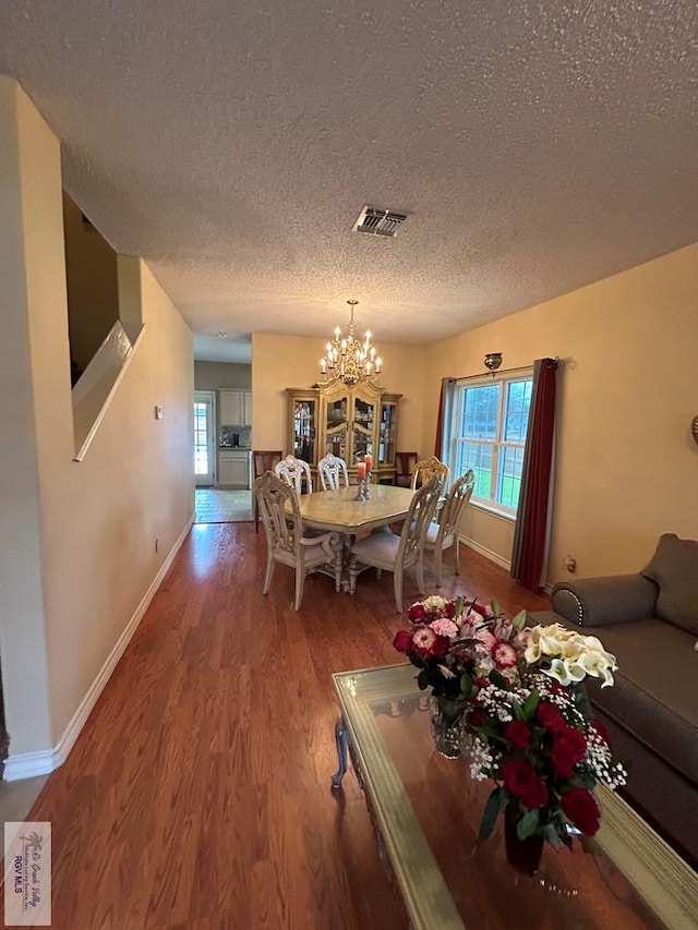 dining area with hardwood / wood-style flooring, a textured ceiling, and a notable chandelier