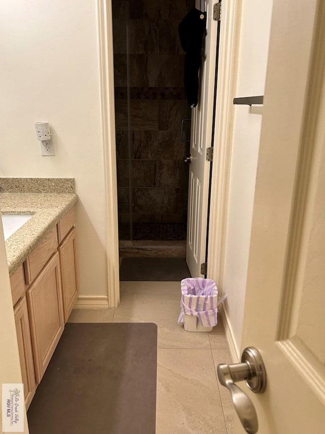 bathroom featuring a shower with door, vanity, and tile patterned floors