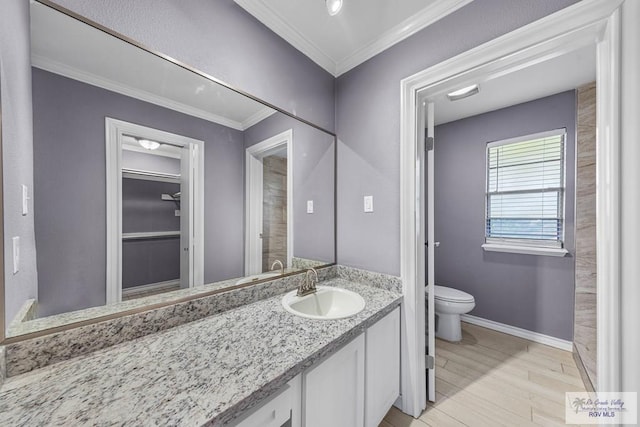 bathroom with toilet, vanity, ornamental molding, and hardwood / wood-style flooring