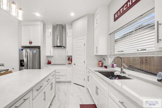 122 Heron Dr, Los Fresnos, TX 78566 - kitchen with stainless steel fridge with ice dispenser, wall chimney range hood, recessed lighting, light marble finish floors, and white cabinets