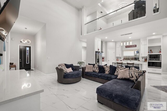 122 Heron Dr, Los Fresnos, TX 78566 - living room featuring light marble finish flooring, a towering ceiling, and recessed lighting