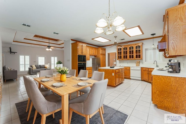 tiled dining space with ornamental molding, sink, ceiling fan, and a tray ceiling