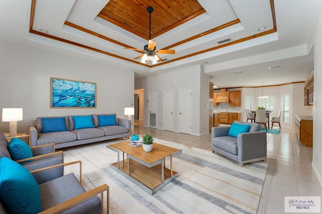 tiled living room featuring crown molding, a tray ceiling, and ceiling fan with notable chandelier