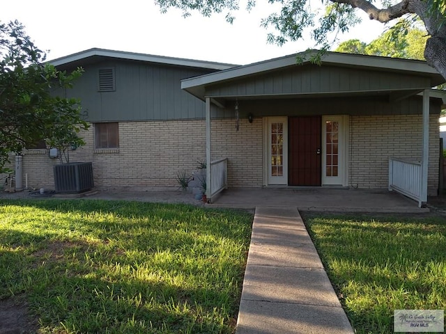 back of house featuring cooling unit, a patio area, and a lawn