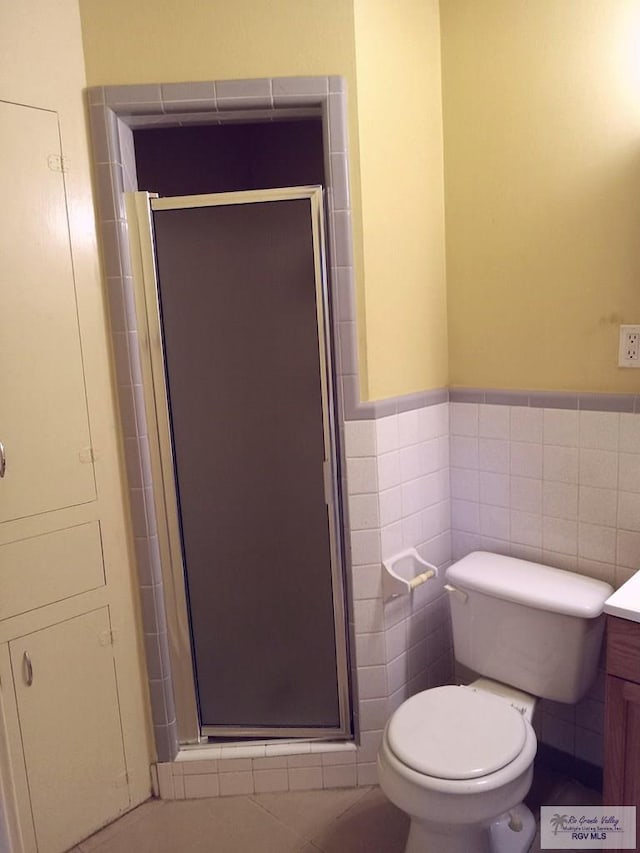 bathroom with tile patterned flooring, an enclosed shower, toilet, vanity, and tile walls