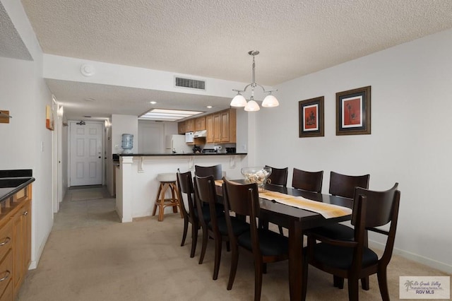 dining room featuring a textured ceiling, light colored carpet, and an inviting chandelier