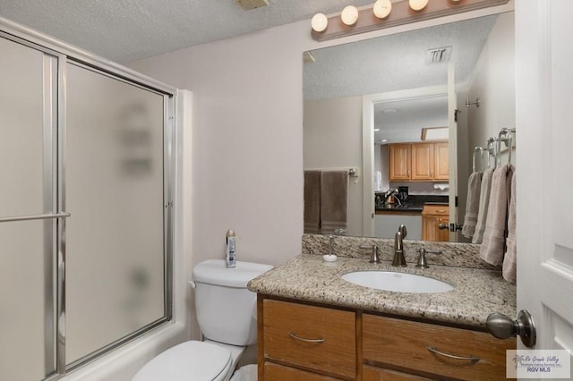 full bathroom with vanity, a textured ceiling, toilet, and bath / shower combo with glass door