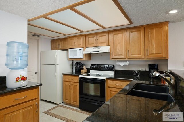 kitchen featuring a textured ceiling, white appliances, dark stone countertops, and sink