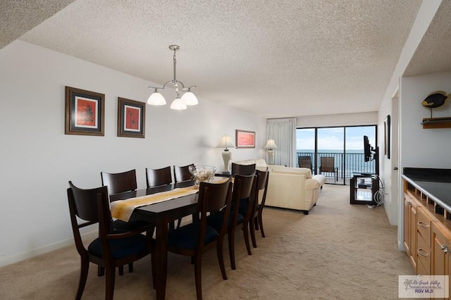 dining space with light carpet, a textured ceiling, and an inviting chandelier