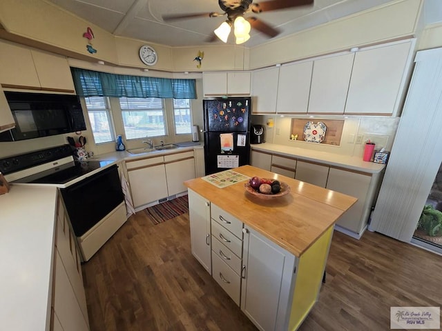 kitchen featuring sink, wooden counters, white cabinetry, a center island, and black appliances