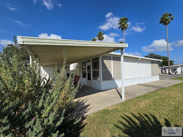 view of side of property featuring a carport, a sunroom, and a yard