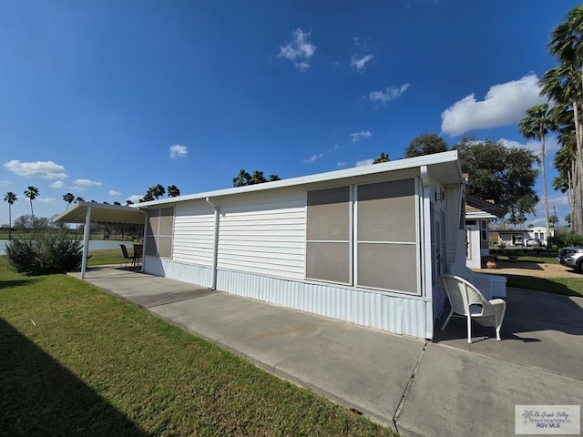 view of side of home featuring a carport and a lawn