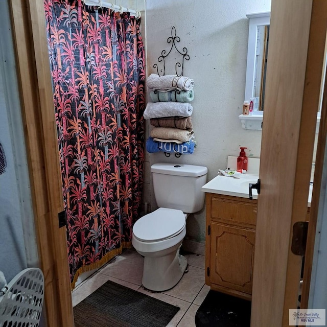 bathroom featuring toilet, vanity, tile patterned floors, and walk in shower