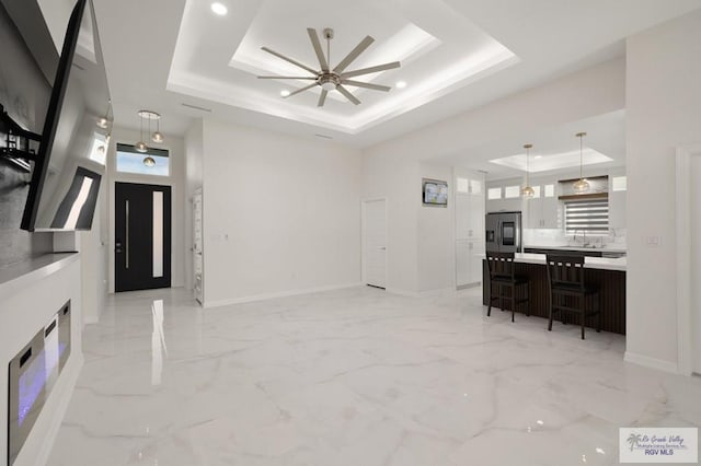entrance foyer with a ceiling fan, baseboards, a raised ceiling, and marble finish floor