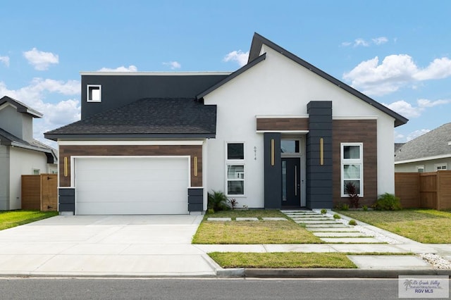 contemporary house with concrete driveway, fence, a front yard, and a garage