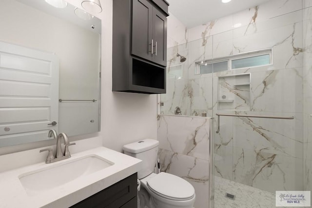 bathroom featuring a marble finish shower, vanity, and toilet