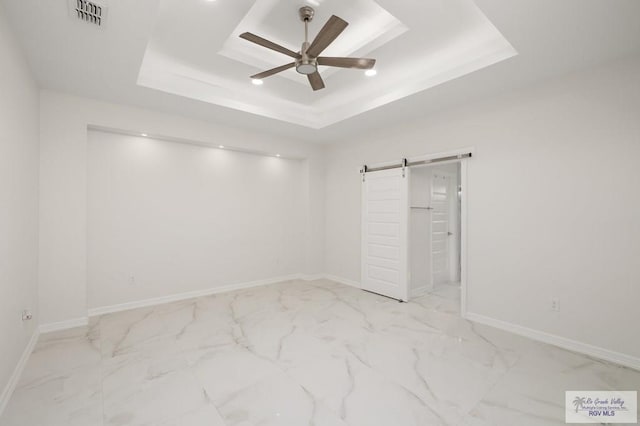 unfurnished bedroom with a raised ceiling, marble finish floor, a barn door, and visible vents