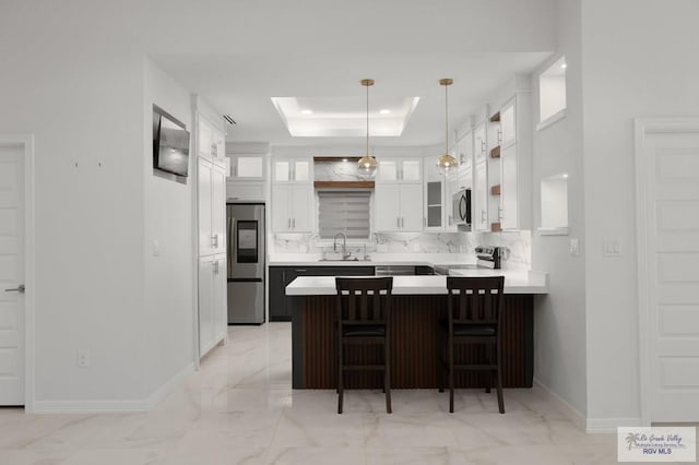 kitchen featuring marble finish floor, a peninsula, glass insert cabinets, a sink, and appliances with stainless steel finishes