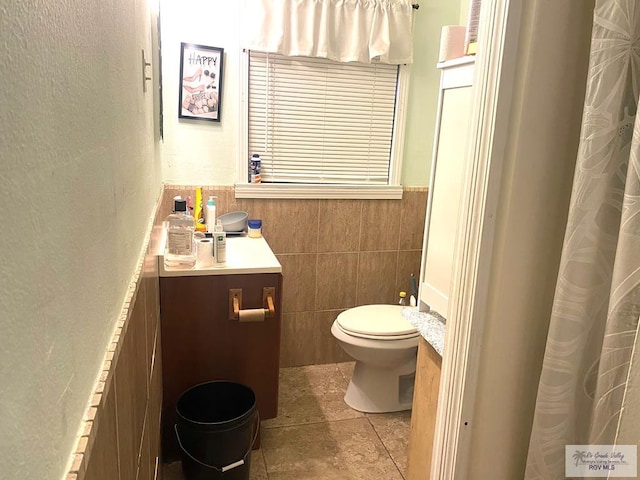 full bath featuring tile patterned flooring, toilet, vanity, and tile walls