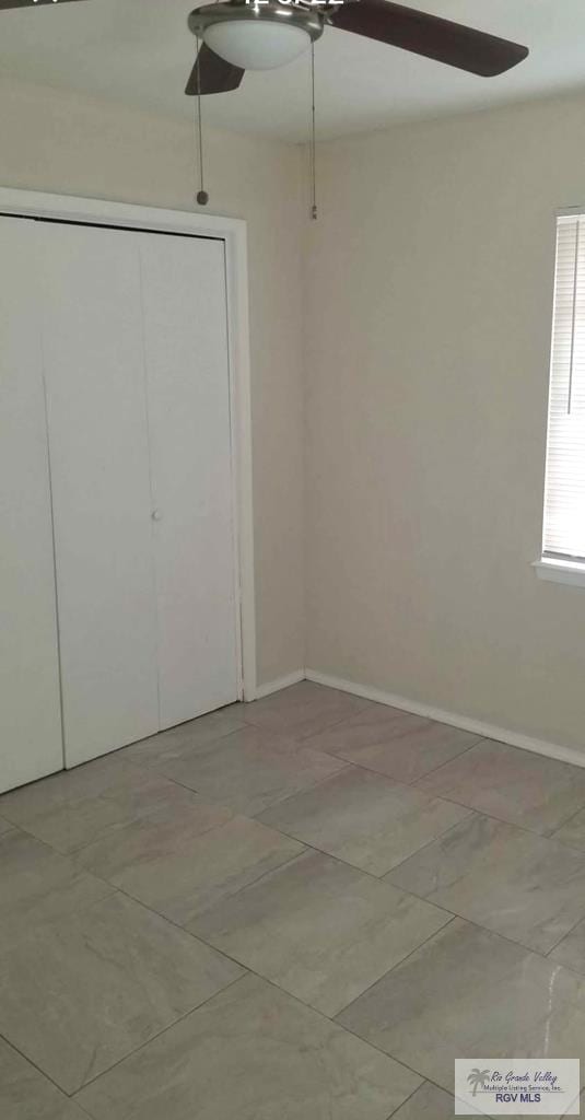 unfurnished bedroom with a closet, a ceiling fan, and baseboards