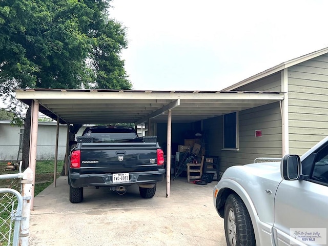 view of parking with an attached carport and fence