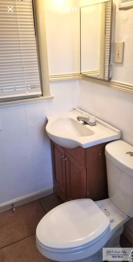 half bath featuring tile patterned floors, toilet, and vanity