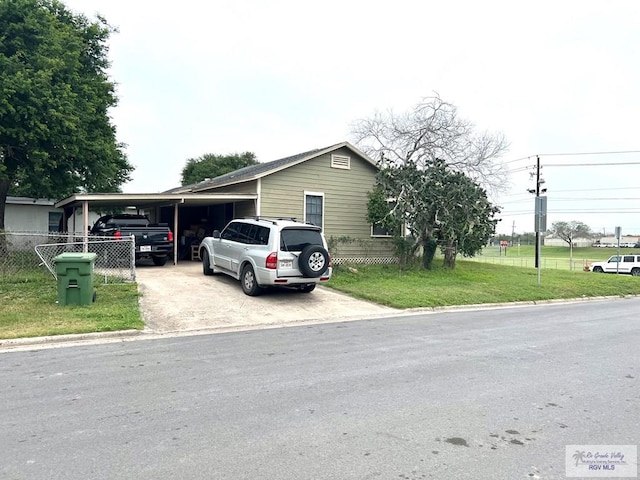 view of front of home featuring driveway, a carport, a front lawn, and fence