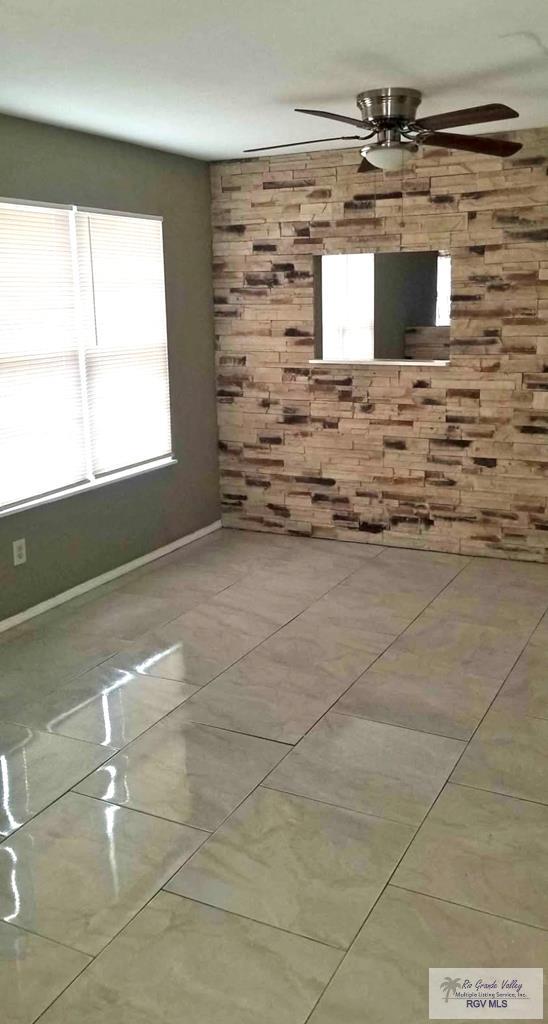 tiled empty room featuring a ceiling fan