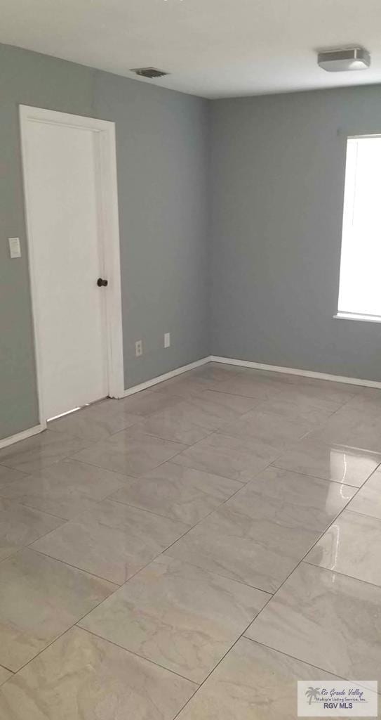 spare room featuring marble finish floor and baseboards