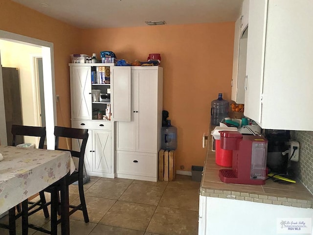 kitchen with tile patterned flooring, visible vents, tile counters, white cabinets, and open shelves