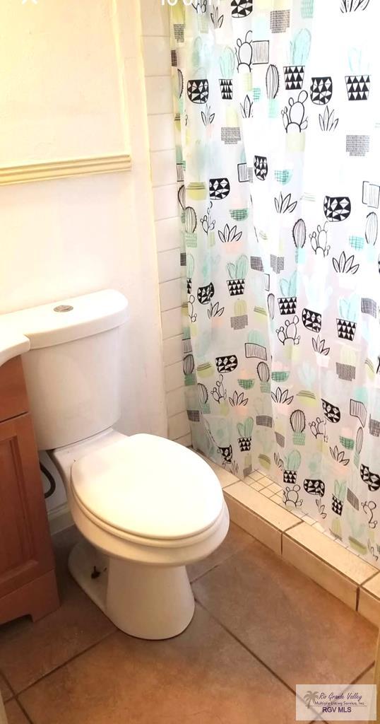 bathroom featuring tile patterned floors, a shower stall, toilet, and vanity