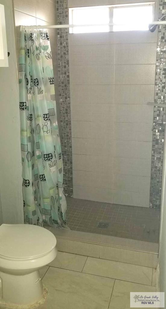 bathroom featuring tile patterned floors, toilet, and a stall shower