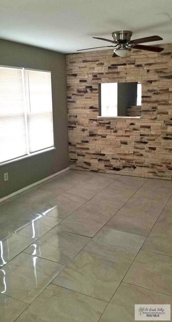 unfurnished room featuring tile patterned flooring, baseboards, and ceiling fan