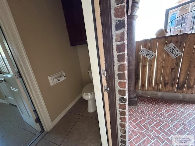 bathroom featuring wooden walls, tile patterned floors, and toilet